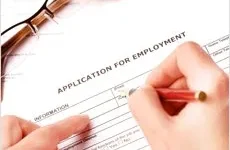 Résumé Writing A person fills out an application for employment form with a pencil; eyeglasses rest nearby on the paper.