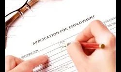 Résumé Writing A person fills out an application for employment form with a pencil; eyeglasses rest nearby on the paper.