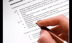 Professional Editing A hand holding a pen is poised over a printed resume, highlighting the professional experience section.